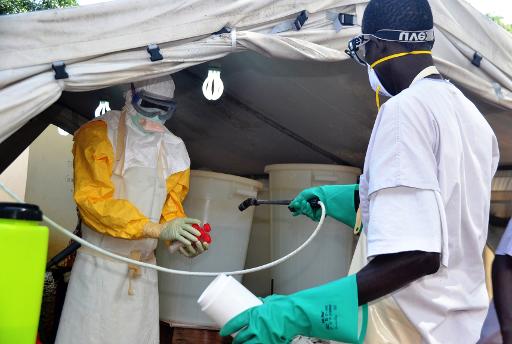 Usando trajes especiais, funcion&aacute;rio de sa&uacute;de tem as m&atilde;os desinfectadas em um centro de tratamento contra o Ebola da organiza&ccedil;&atilde;o MSF, em Conacri, Guin&eacute;. Foto: AFP/CELLOU BINANI/AFP/CELLOU BINANI