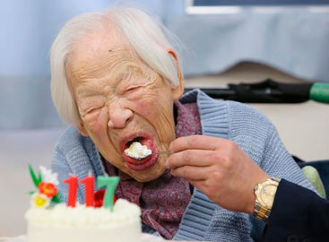 Misao prova o bolo de aniversário na casa onde é cuidada, em Osaka. Foto: Jiji Press/AFP Photo/
