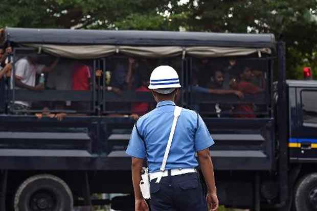 Oficial da Marinha da Malásia observa veículo com imigrantes bengaleses em centro de detenção temporário em 13 de maio em Langkawi. Foto: Manan Vatsyayana/AFP/ Oficial da Marinha da Malásia observa veículo com imigrantes bengaleses em centro de detenção temporário em 13 de maio em Langkawi. Foto: Manan Vatsyayana/AFP/