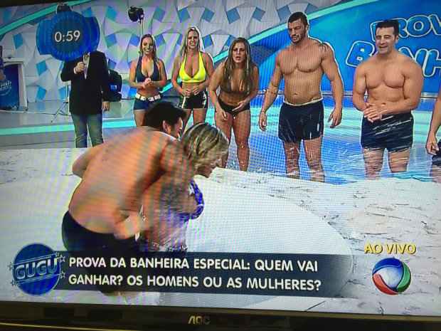 Cantor Léo Santana segura campeã de halterofilismo na hora de pegar os sabonetes. Créditos: Record/Reprodução/ Cantor Léo Santana segura campeã de halterofilismo na hora de pegar os sabonetes. Créditos: Record/Reprodução/