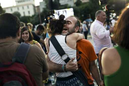 Gregos comemoram, na praça Klafthmonos, em Atenas, após as primeiras pesquisas de urna do referendo. Foto: Angelos Tzortzinis/AFP/