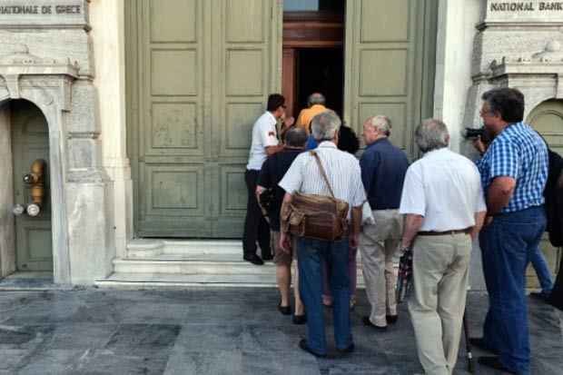 Correntistas entram na agência de um banco em Atenas. Foto: Louisa Gouliamaki/AFP/