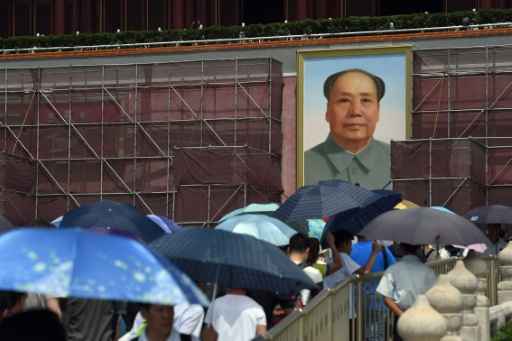 Turistas usam guarda-sóis para se proteger do calor enquanto passeiam em frente ao retrato do líder comunista Mao Tsé-Tung em Pequim, no dia 23 de julho de 2015. Foto:Greg Baker/ AFP