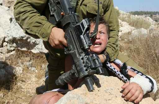 Um soldado israelense imobiliza um menino palestino durante enfrentamentos entre manifestantes, em Nabi Saleh, Cisjordânia, no dia 28 de agosto de 2015. Fotos: Abbas Momani/AFP/