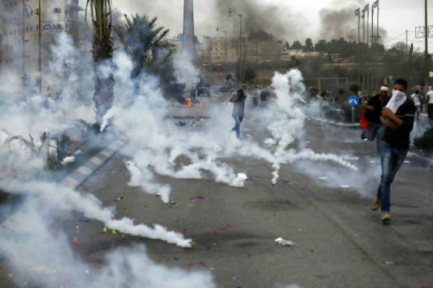 Manifestantes palestinos fogem de gás lacrimogênio lançado pela polícia na Cisjordânia, em confronto que matou uma mulher palestina. Foto: AFP Abbas Momani