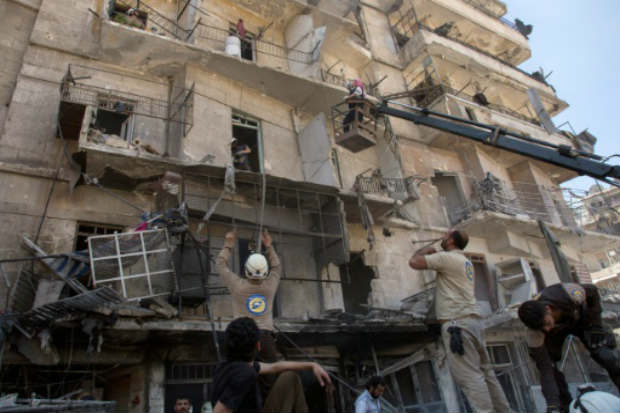 Funcion&aacute;rios da defesa civil evacuam pessoas ap&oacute;s bombardeio, em Aleppo. Foto: AFP KARAM AL-MASRI/