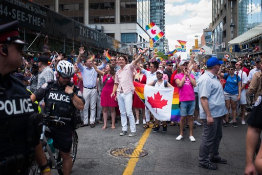 Trudeau agita bandeira, com calça branca e camisa salmão. Foto: Ian Willms/Getty Images/AFP/ Trudeau agita bandeira, com calça branca e camisa salmão. Foto: Ian Willms/Getty Images/AFP/