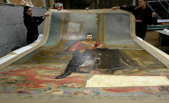 Foto tirada em S&atilde;o Petesburgo no dia 17 de novembro de 2016 mostra os restauradores do Stieglitz Art and Industry Academy expondo um retrato do czar Nicolau II, feito por Ilya Galkin (1896), que foi descoberto debaixo da pintura de L&ecirc;nin. Foto: Olga Maltseva/AFP/