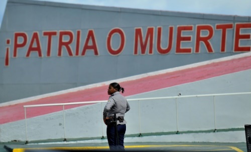 Policial permanece em frente &agrave; frase "P&aacute;tria ou Morte", em Havana, neste s&aacute;bado (26) Foto: AFP YAMIL LAGE/