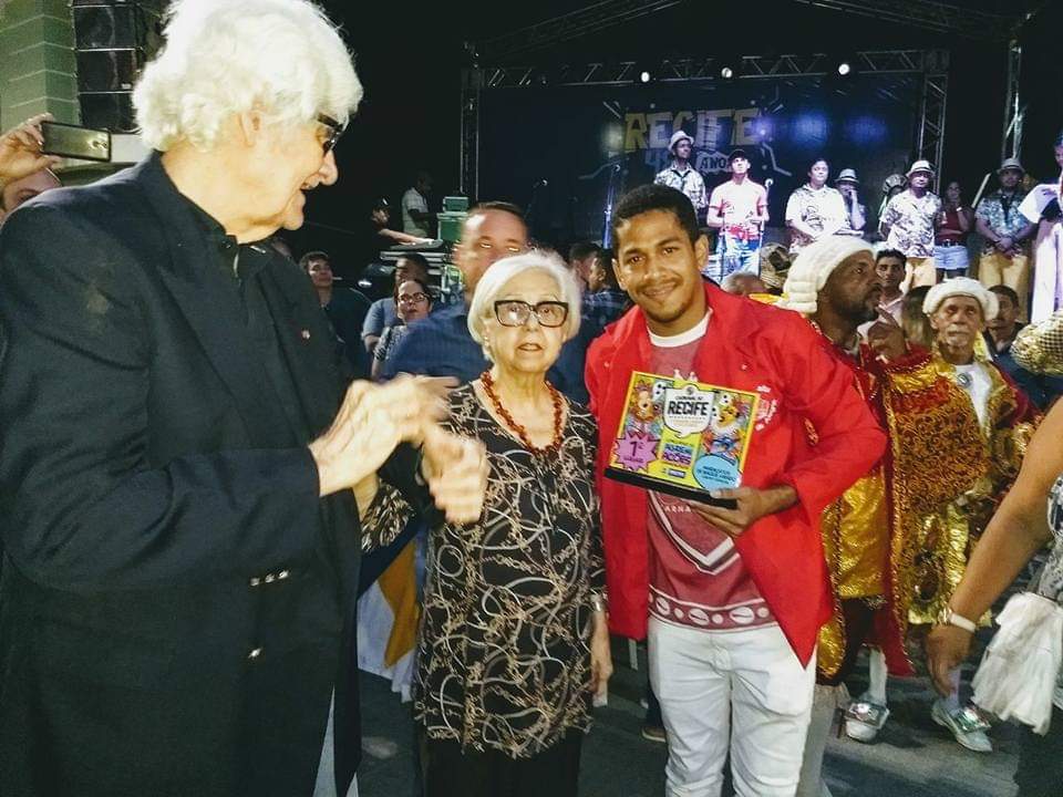 Anderson Santos (presidente do grupo) recebendo o troféu de campeão das mãos da Secretária de Cultura da Prefeitura do Recife, Leda Alves. Foto: Divulgação 