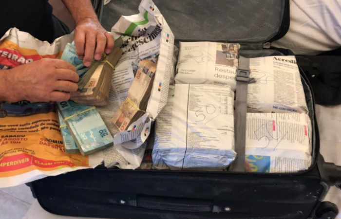 Policiais encontram dinheiro embrulhado em jornal, dentro de mala, em casa de mulher presa durante operação em Goiás, Goiânia (Foto: TV Anhanguera/ Reprodução)/Policiais encontram dinheiro embrulhado em jornal, dentro de mala, em casa de mulher presa durante operação em Goiás, Goiânia (Foto: TV Anhanguera/ Reprodução)