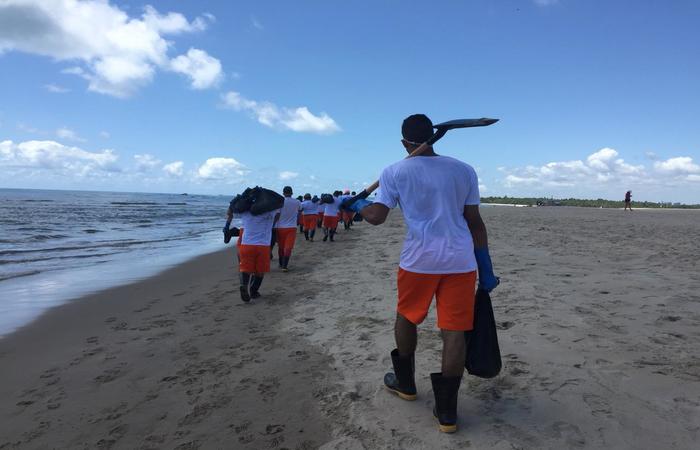 Detentos do semiaberto se voluntariam para retirar manchas de óleo da praia. 