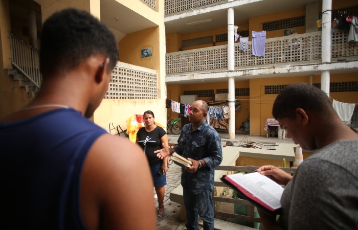 Moradores improvisam culto evangélico em um bloco de apartamentos na comunidade