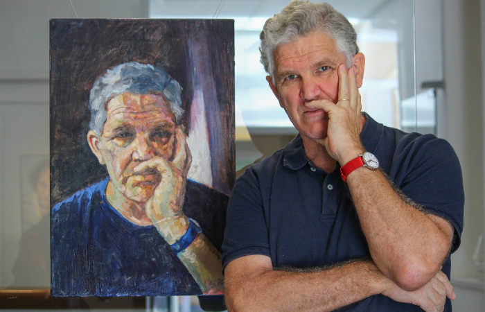 Roberto Ploeg ao lado do quadro Autorretrato quando triste (2019)