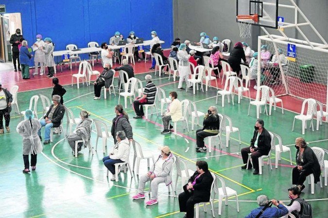/Vacinação em quadra de esportes na Colômbia: sintomas foram mais comuns em mulheres e em pessoas com menos de 50 anos. Foto: Raul ARBOLEDA/AFp /Vacinação em quadra de esportes na Colômbia: sintomas foram mais comuns em mulheres e em pessoas com menos de 50 anos. Foto: Raul ARBOLEDA/AFp