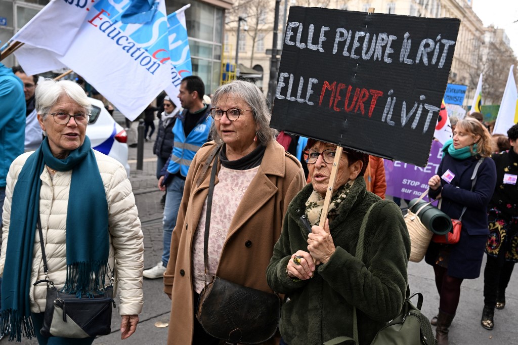 No protesto, mulher levanta um cartaz que diz: "Ela chora, ele ri, ela morre, ele vive"/Foto: Nicolas TUCAT / AFP No protesto, mulher levanta um cartaz que diz: "Ela chora, ele ri, ela morre, ele vive"/Foto: Nicolas TUCAT / AFP