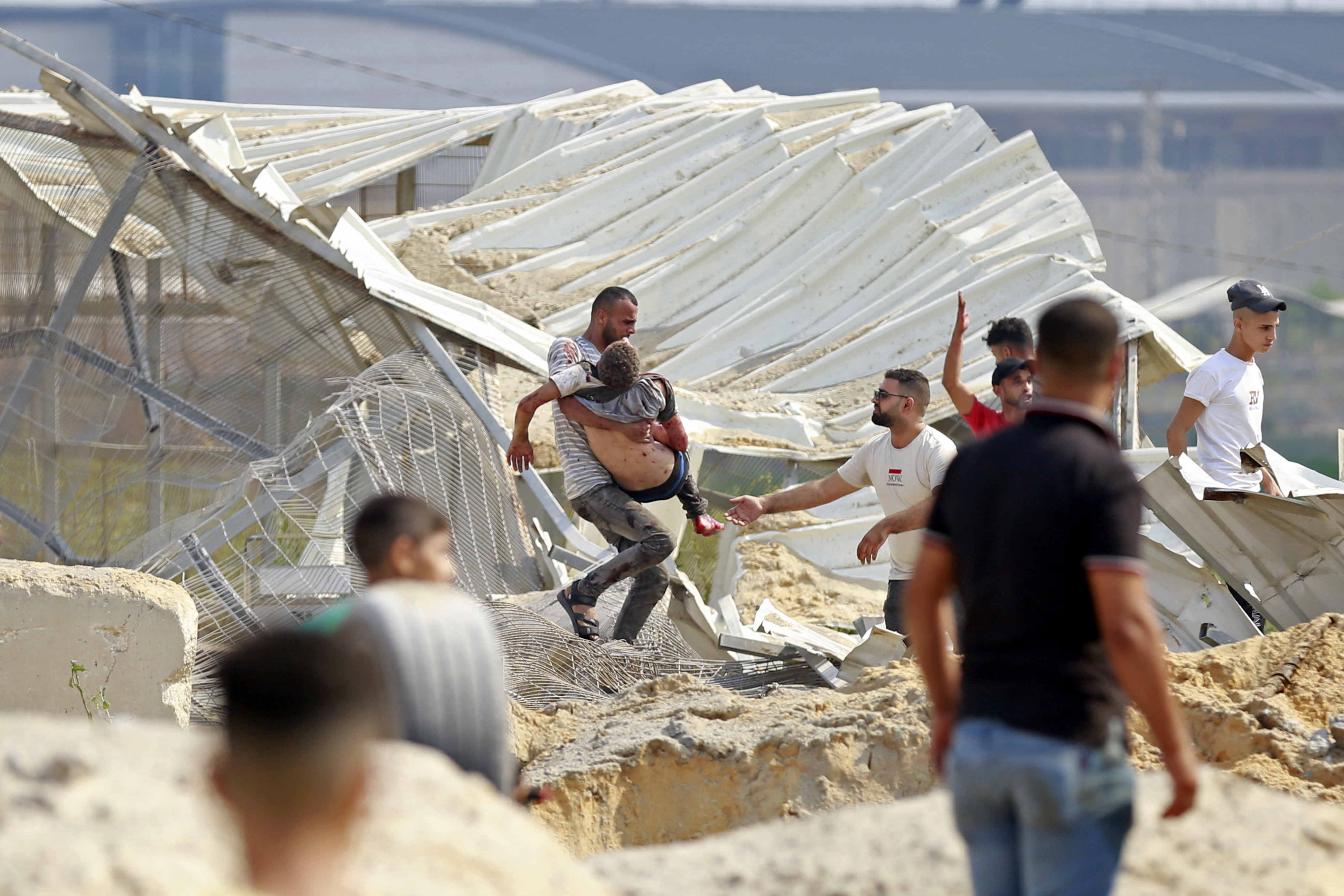 Um homem carrega um palestino atingido em um ataque aéreo israelense na passagem de Erez entre Israel e o norte da Faixa de Gaza/BASHAR TALEB / AFP Um homem carrega um palestino atingido em um ataque aéreo israelense na passagem de Erez entre Israel e o norte da Faixa de Gaza/BASHAR TALEB / AFP