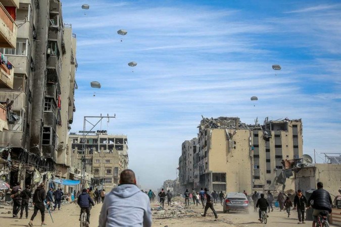 Palestinos correm para pegar alimentos jogados no ar/Foto: AFP