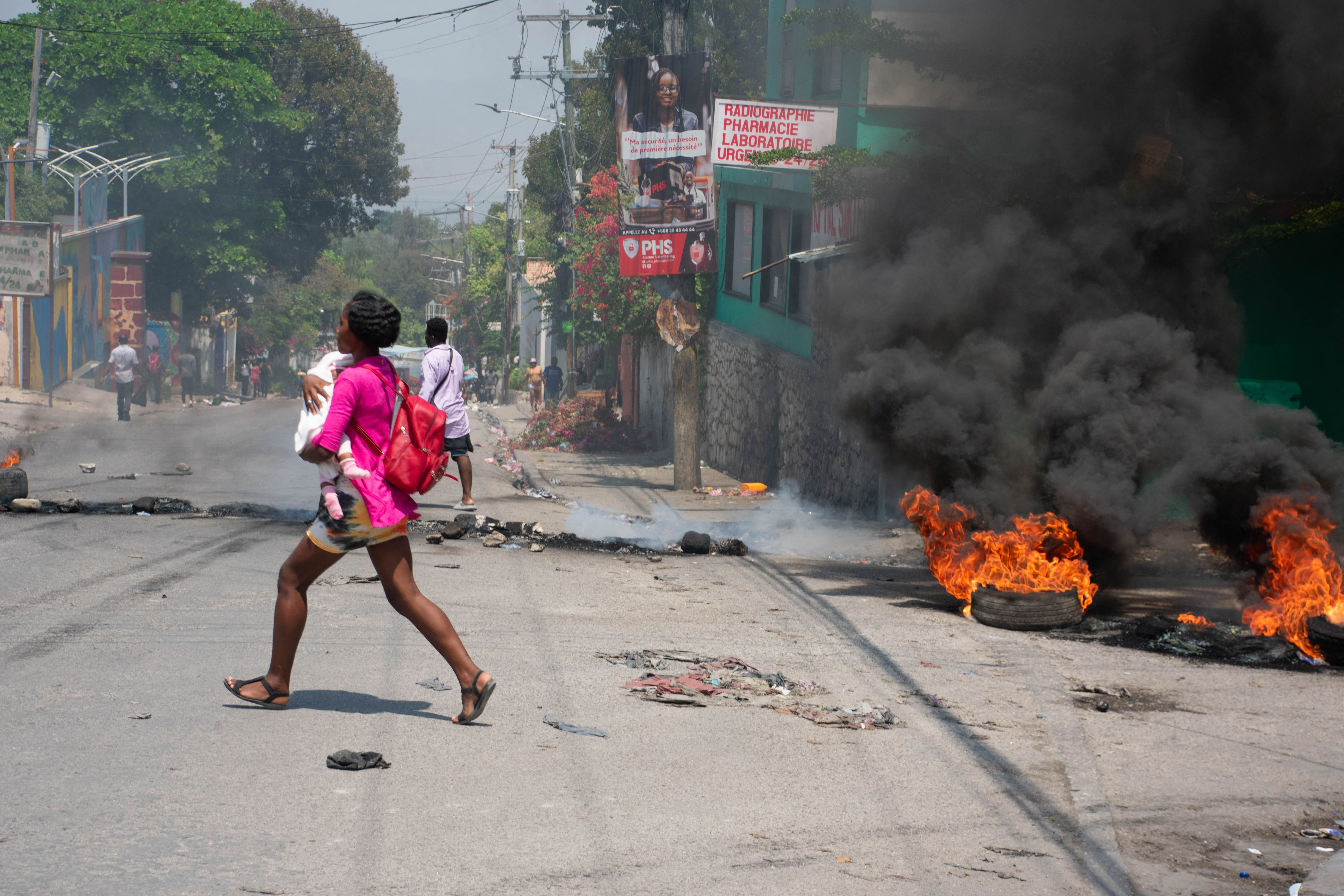 Uma mulher carregando uma criança foge depois que tiros foram ouvidos em Porto Príncipe, Haiti, nesta quarta-feira (20)/Foto: CLARENS SIFFROY / AFP Uma mulher carregando uma criança foge depois que tiros foram ouvidos em Porto Príncipe, Haiti, nesta quarta-feira (20)/Foto: CLARENS SIFFROY / AFP