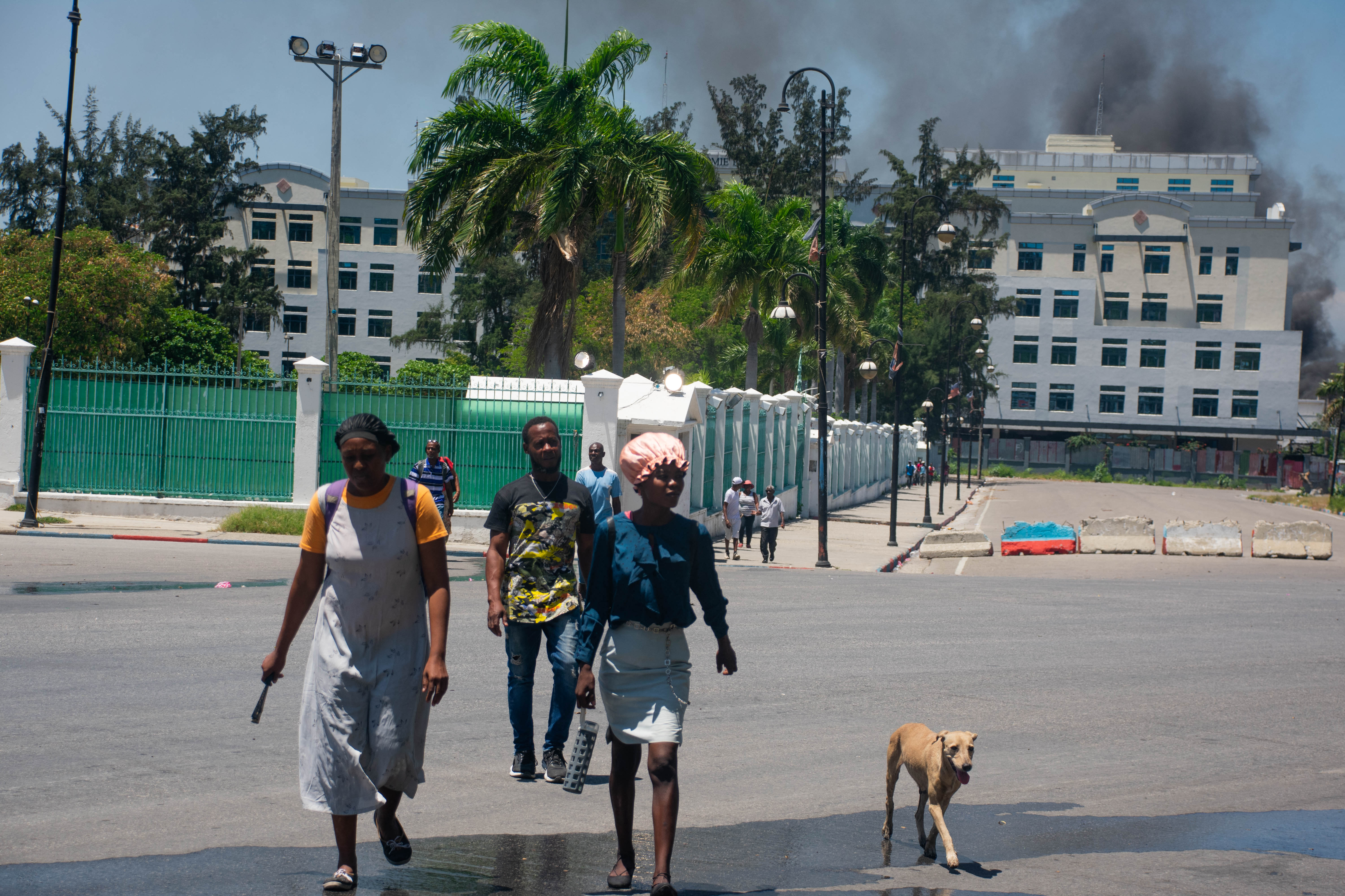 Enquanto a fumaça sobe do prédio do Ministério das Finanças atrás delas, pessoas deixam a área após ouvirem tiros de gangues armadas perto do Palácio Nacional em Porto Príncipe, no Haiti/Foto: CLARENS SIFFROY / AFP Enquanto a fumaça sobe do prédio do Ministério das Finanças atrás delas, pessoas deixam a área após ouvirem tiros de gangues armadas perto do Palácio Nacional em Porto Príncipe, no Haiti/Foto: CLARENS SIFFROY / AFP