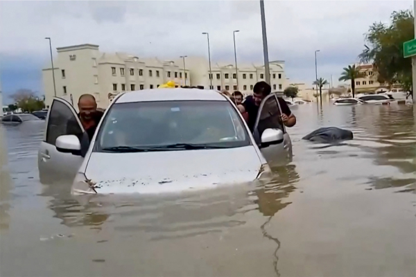 Neste vídeo da AFPTV, pessoas empurram um carro encalhado ao longo de uma inundada/Crédito: ATIF BHATTI / ESN / AFP Neste vídeo da AFPTV, pessoas empurram um carro encalhado ao longo de uma inundada/Crédito: ATIF BHATTI / ESN / AFP
