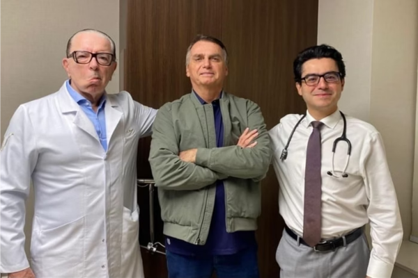 Jair Bolsonaro, de braços cruzados, entre dois médicos/Crédito: Reprodução / Redes sociais