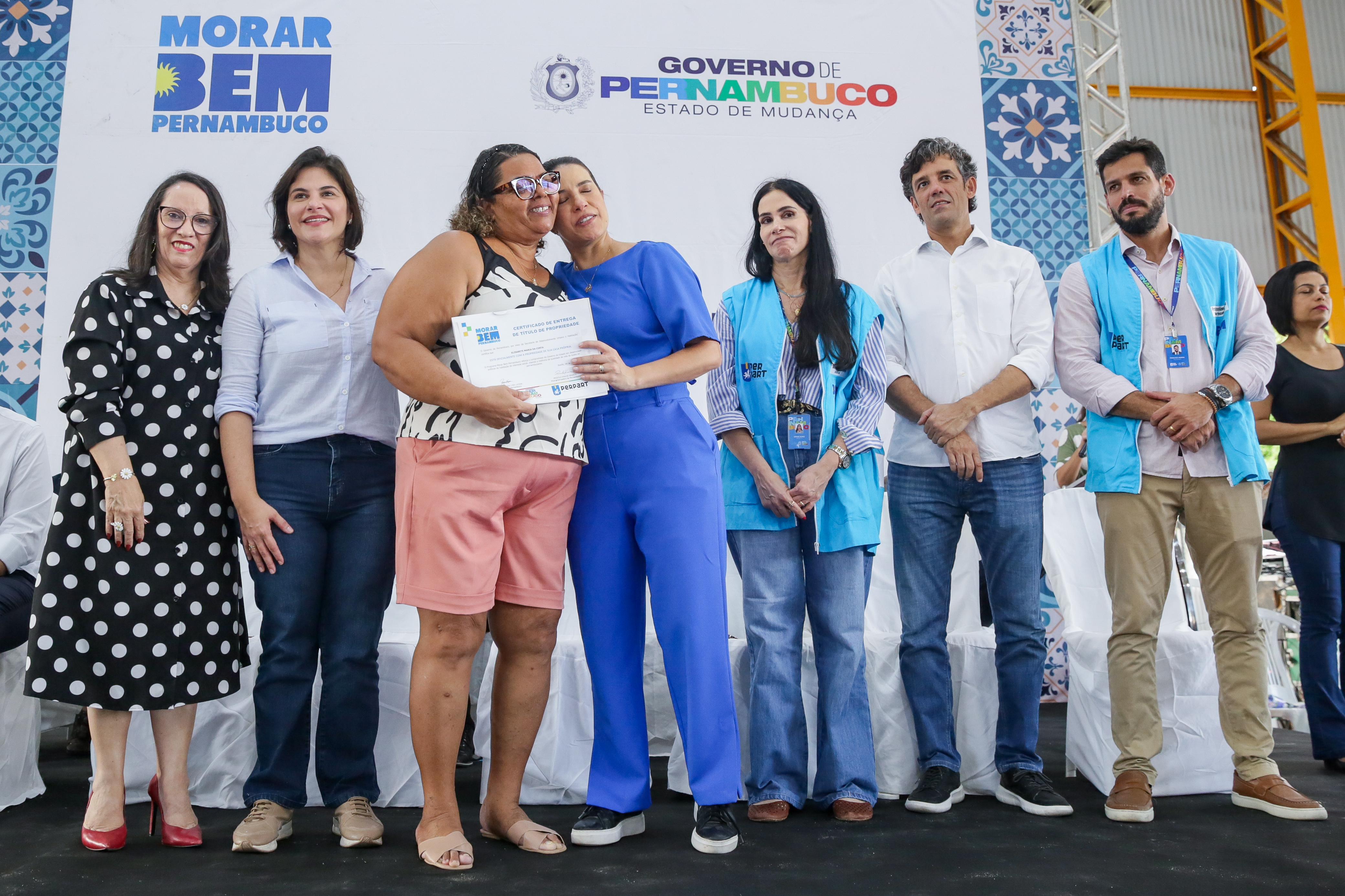 A moradora Elisabete Maria da Costa recebendo seu título de propriedade