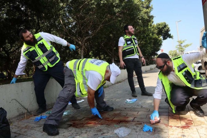 Socorristas israelenses limpam sangue no local de um suposto ataque de facada em Holon, no subúrbio ao sul de Tel Aviv, em 4 de agosto de 2024. Duas pessoas morreram e outras duas ficaram feridas no ataque, o serviço médico de emergência de Israel disse o serviço, com a polícia relatando que um suspeito palestino foi "neutralizado"/Foto: GIL COHEN-MAGEN / AFP Socorristas israelenses limpam sangue no local de um suposto ataque de facada em Holon, no subúrbio ao sul de Tel Aviv, em 4 de agosto de 2024. Duas pessoas morreram e outras duas ficaram feridas no ataque, o serviço médico de emergência de Israel disse o serviço, com a polícia relatando que um suspeito palestino foi "neutralizado"/Foto: GIL COHEN-MAGEN / AFP