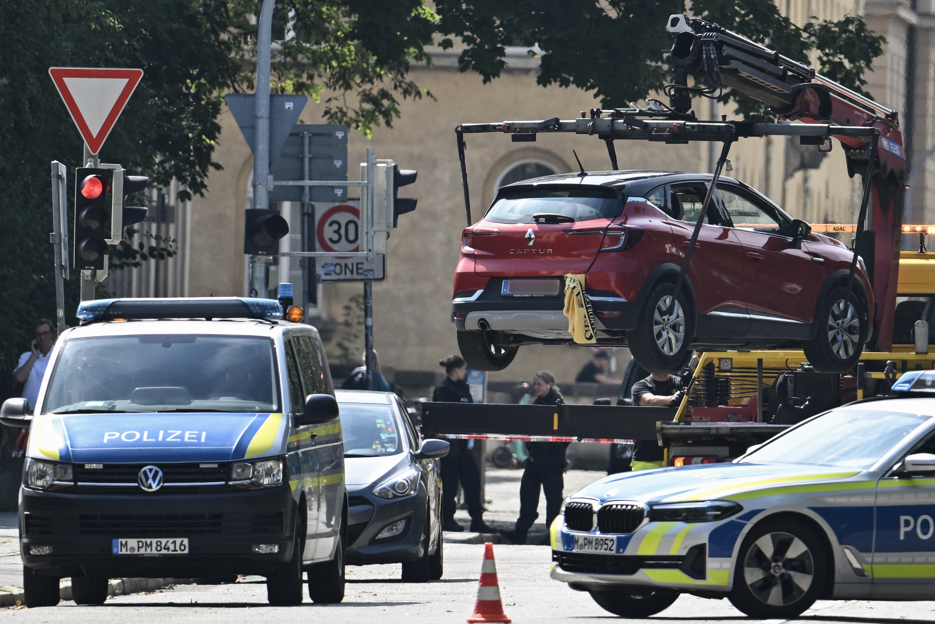 Policiais removem um carro com placa austríaca com um guindaste enquanto protegem a área após um tiroteio perto do consulado israelense/Foto: LUKAS BARTH-TUTTAS / AFP Policiais removem um carro com placa austríaca com um guindaste enquanto protegem a área após um tiroteio perto do consulado israelense/Foto: LUKAS BARTH-TUTTAS / AFP