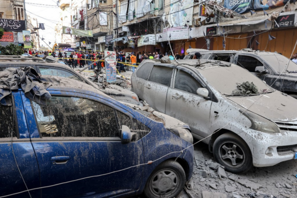 Pessoas atrás de uma área fechada em uma rua sob um prédio residencial cujos dois últimos andares foram atingidos por um ataque israelense/Créditos: ANWAR AMRO / AFP Pessoas atrás de uma área fechada em uma rua sob um prédio residencial cujos dois últimos andares foram atingidos por um ataque israelense/Créditos: ANWAR AMRO / AFP