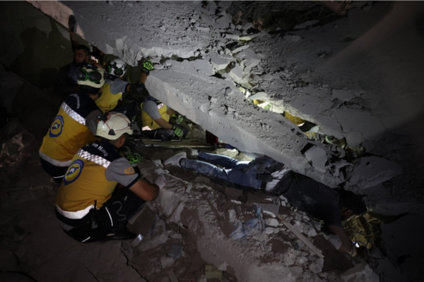 Membros da força de defesa civil dos Capacetes Brancos da Síria trabalham na remoção de vítimas sob os escombros de uma oficina de móveis nos arredores da cidade de Idlib, no noroeste da Síria, controlada pelos rebeldes/Crédito: Omar HAJ KADOUR / AFP