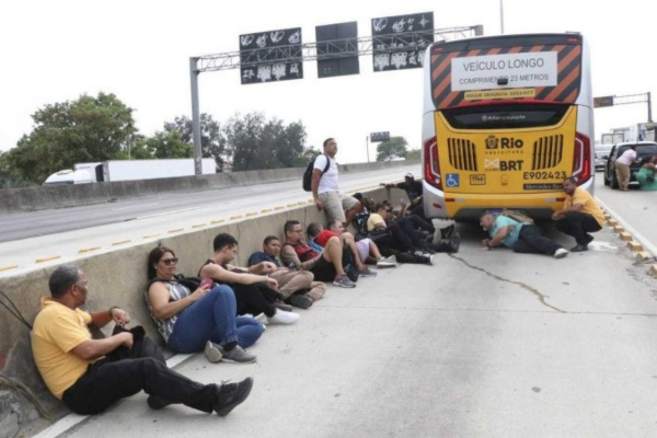 Sem saída: no meio do fogo cruzado, passageiros de um ônibus tiveram que buscar proteção na mureta divisória da Avenida Brasil, que foi interditada/Crédito: José Lucena/AE