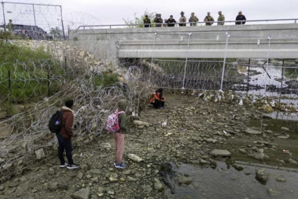 Em Eagle Pass, no Texas, soldados e policiais observam imigrantes que cruzaram o Rio Grande para tentar entrar nos EUA/Crédito: Getty Images via AFP Em Eagle Pass, no Texas, soldados e policiais observam imigrantes que cruzaram o Rio Grande para tentar entrar nos EUA/Crédito: Getty Images via AFP