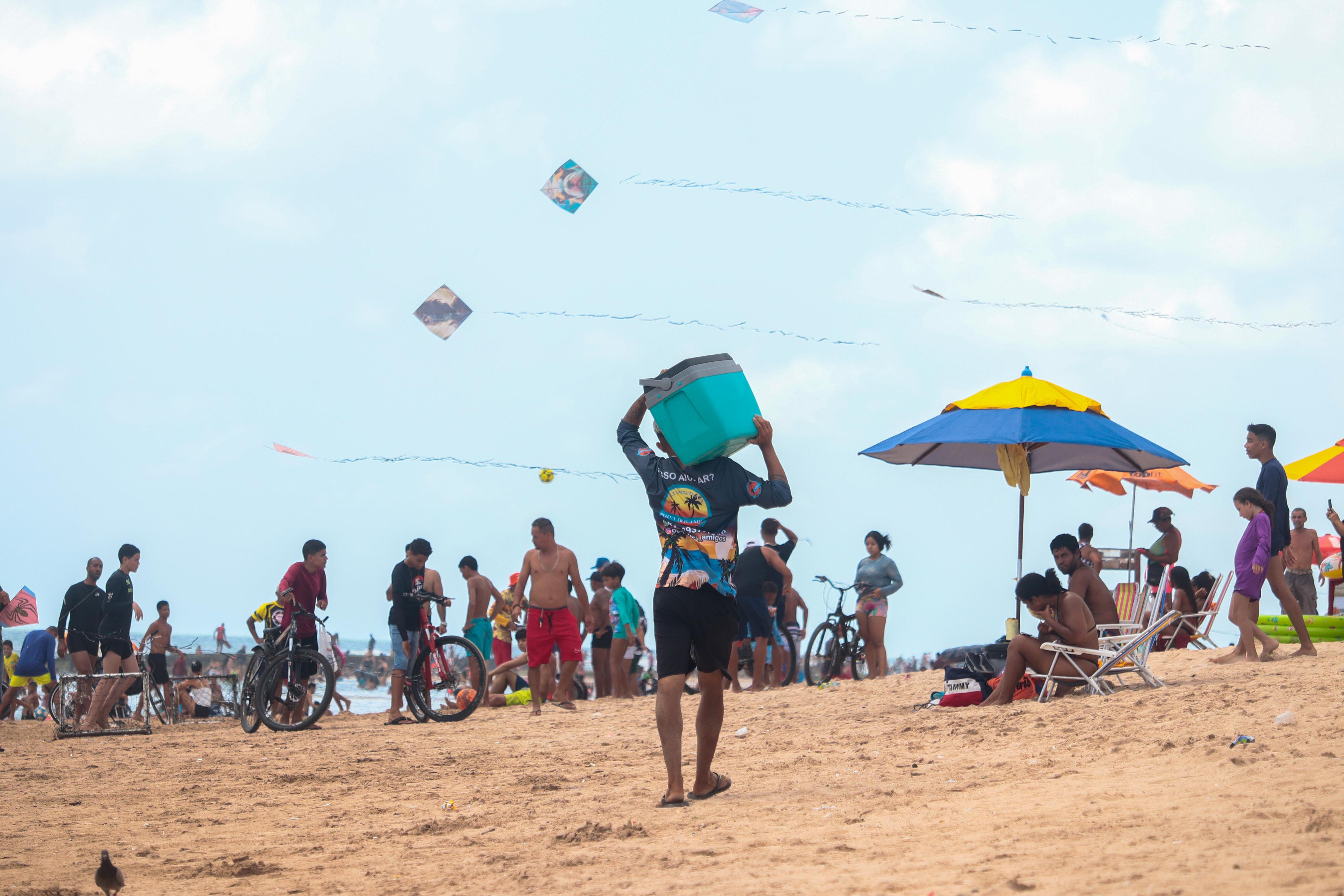 Bicicletas na faixa de areia, crianças jogando bola e brincadeiras com pipas