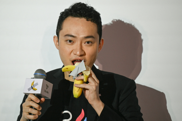 O fundador chinês da criptomoeda Justin Sun come uma banana, obra de arte composta por uma banana fresca presa a uma parede com fita adesiva/Crédito: PETER PARKS / AFP O fundador chinês da criptomoeda Justin Sun come uma banana, obra de arte composta por uma banana fresca presa a uma parede com fita adesiva/Crédito: PETER PARKS / AFP