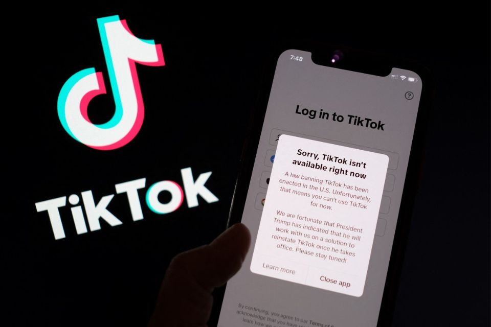 Aplicativo TikTok na tela de um smartphone em frente ao seu logotipo/Foto: CHRIS DELMAS/AFP