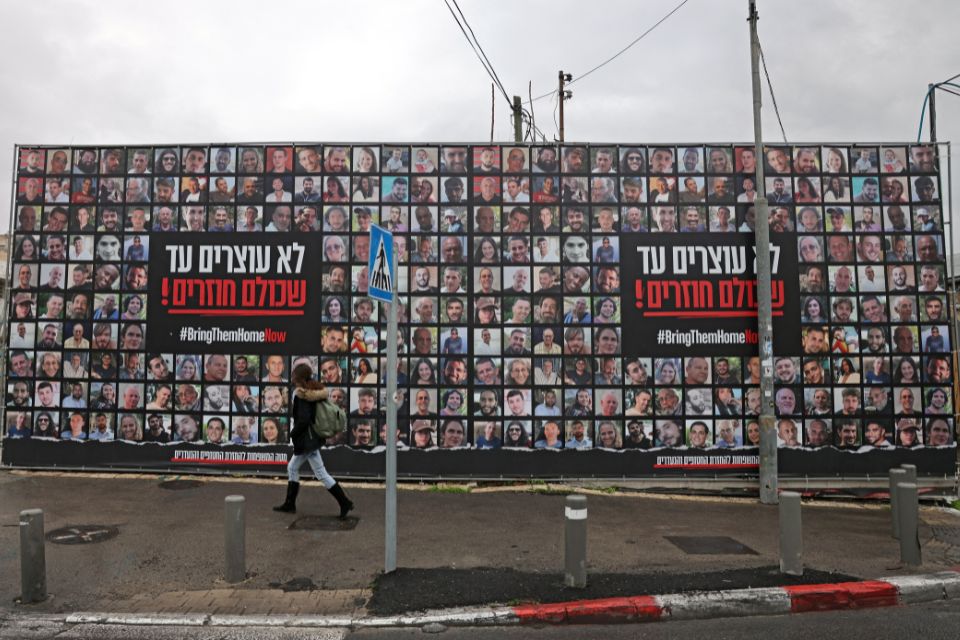 Pedestre passa por retratos de ref&eacute;ns israelenses mantidos na Faixa de Gaza/Foto: Ahmad GHARABLI/AFP
