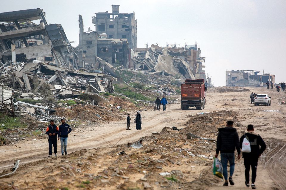 Pessoas caminham e veículos circulam por uma estrada destruída, passando por edifícios desabados no oeste de Beit Lahia, no norte da Faixa de Gaza/Foto: BASHAR TALEB/AFP Pessoas caminham e veículos circulam por uma estrada destruída, passando por edifícios desabados no oeste de Beit Lahia, no norte da Faixa de Gaza/Foto: BASHAR TALEB/AFP