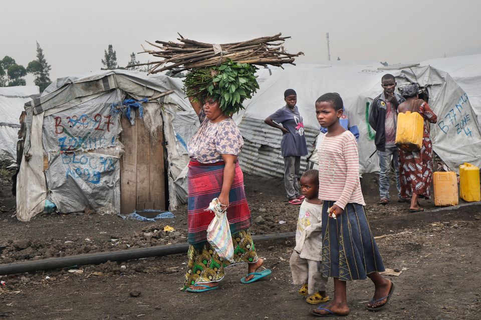 Mulher carrega lenha e vegetais na cabeça ao retornar ao campo de Lushagala para Pessoas Deslocadas Internamente (PDI), na cidade de Goma, capital e maior cidade da província de Kivu do Norte/Foto: Tony KARUMBA/AFP