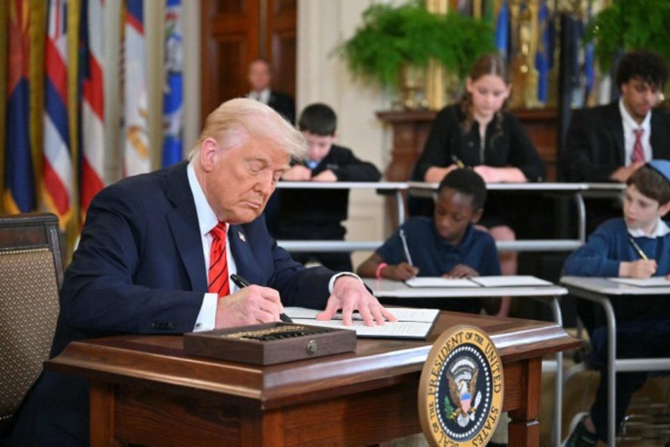 onald Trump firma o documento no Salão Leste da Casa Branca, acompanhado de estudantes: promessa de campanha/Crédito: Mandel Ngan/AFP