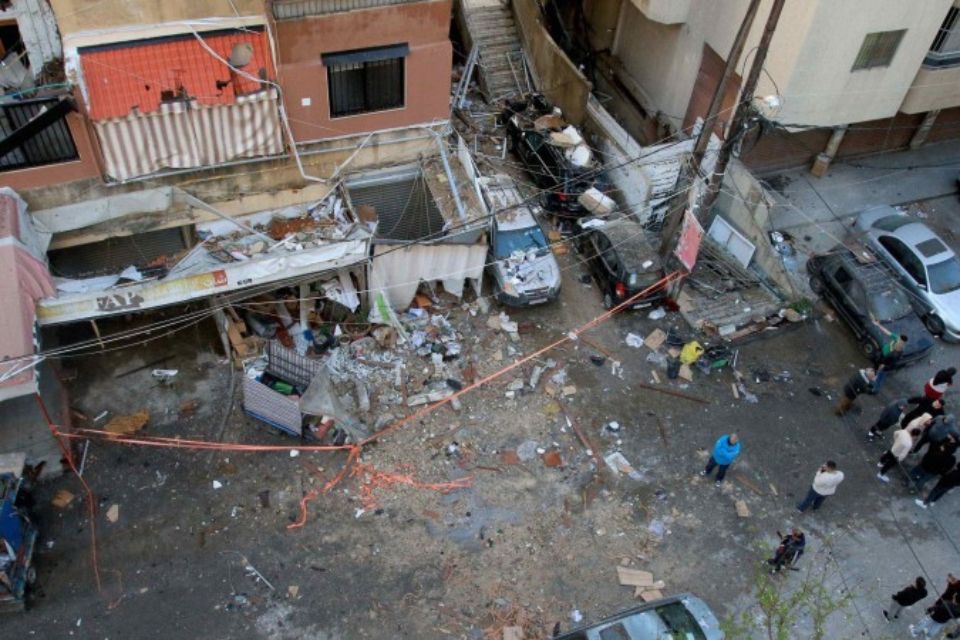 Pessoas ficam perto de destroços em uma rua em frente a um prédio após um ataque israelense em Sidon, em 4 de abril de 2025/Crédito: Mahmoud ZAYYAT/AFP