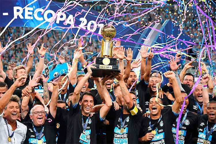 Geromel ergue a taça, jogadores e comissão técnica festejam a conquista sofrida nos pênaltis na Arena