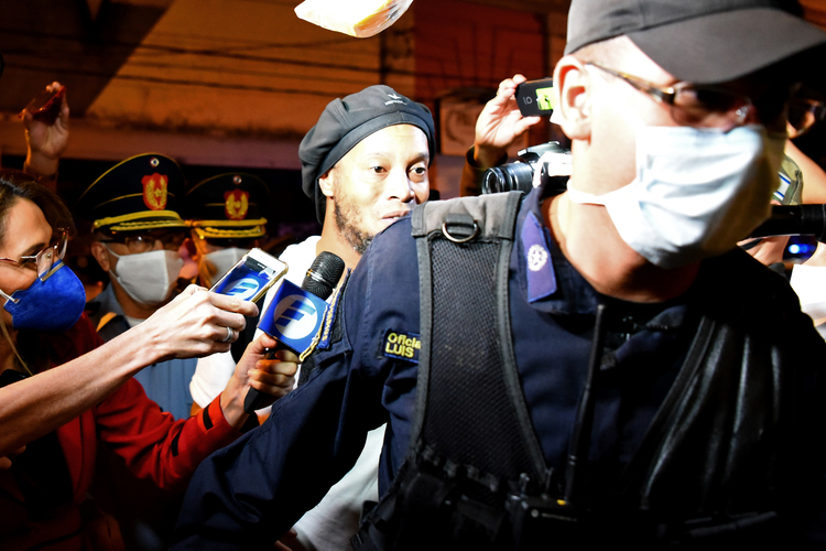 Ronaldinho foi escoltado por policiais que usavam máscaras na chegada ao hotel