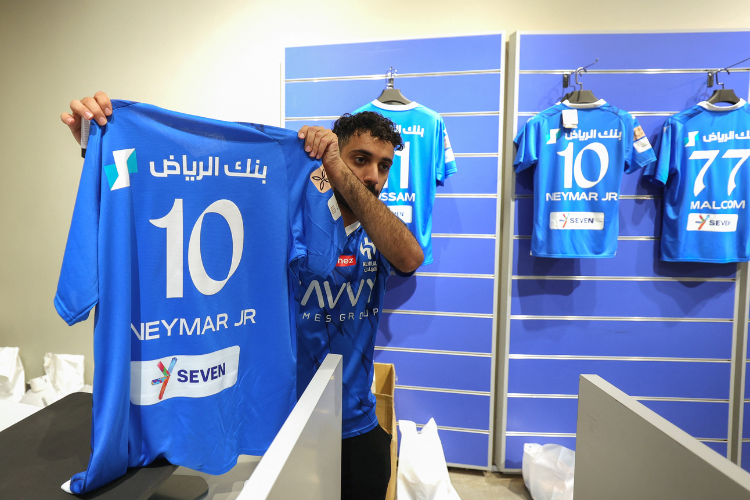 Um funcionário do Al-Hilal imprime o nome e o número do atacante brasileiro Neymar Jr.